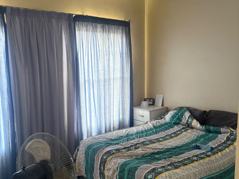 A functional bedroom featuring a ceiling fan and laminate flooring, providing a comfortable and practical living space.