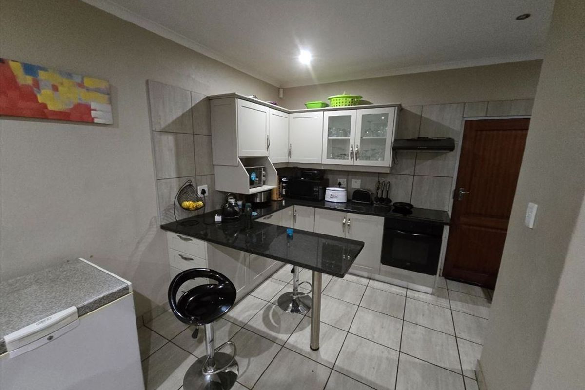 A functional kitchen featuring light-toned cabinetry, dark granite countertops, a breakfast nook, and built-in oven with extractor fan.
