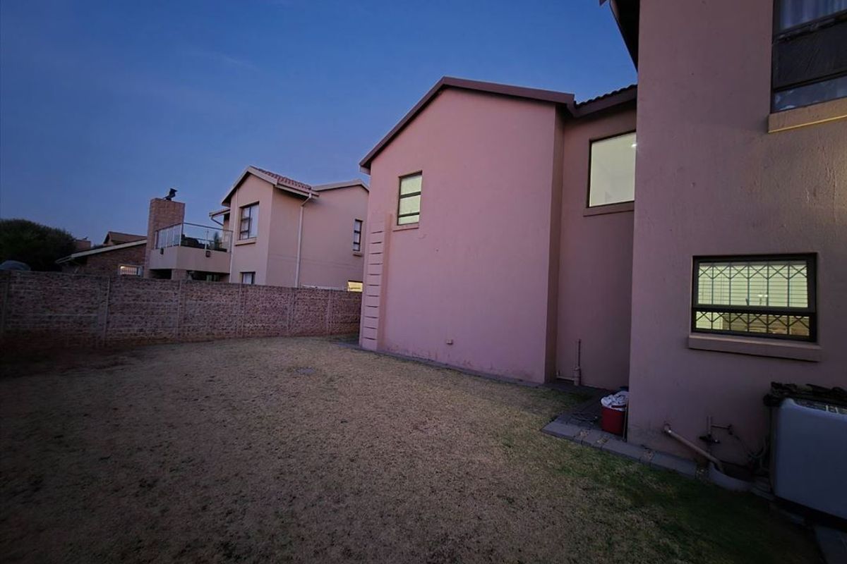 Rear view of the cluster property featuring a private garden area with a brick boundary wall and exterior building facade.