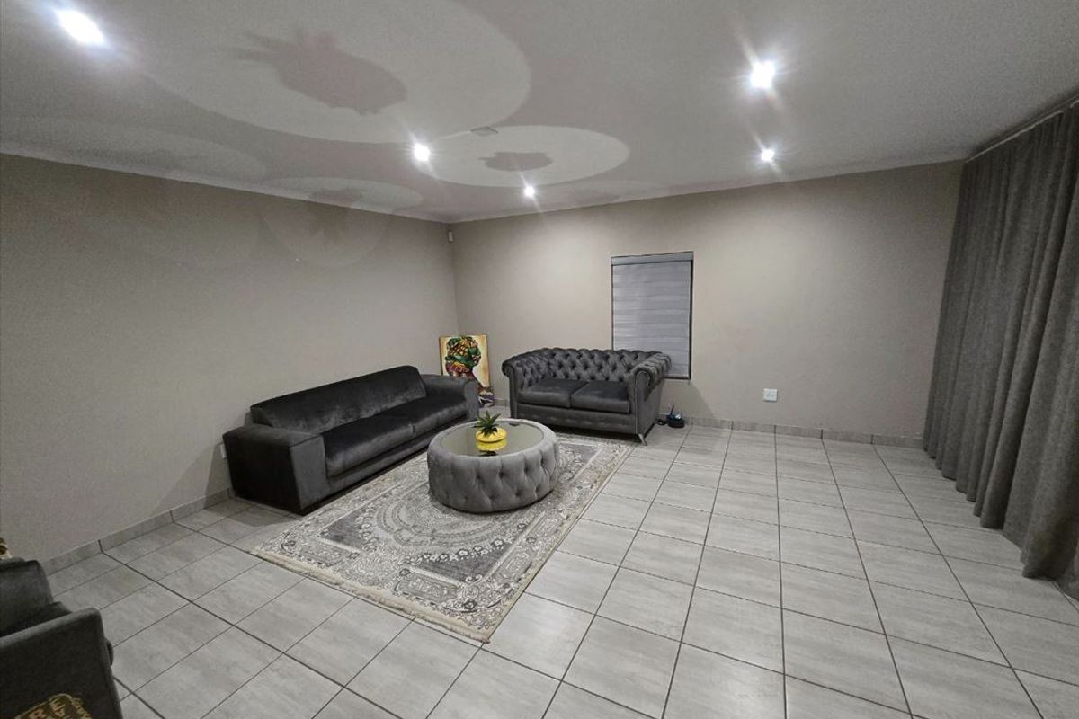 Spacious living room featuring neutral wall tones, tiled flooring, and recessed downlighting, providing a clean and versatile area for relaxation.
