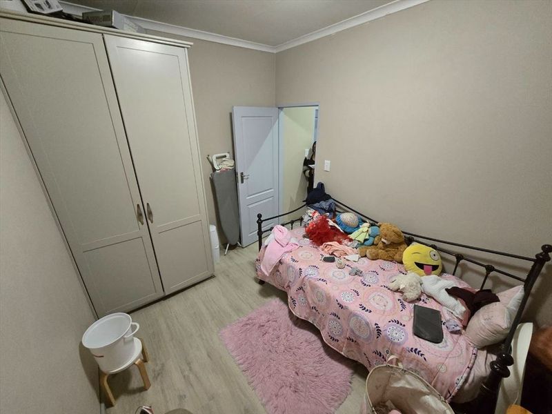 A bedroom featuring laminate flooring, a built-in wardrobe, and coved ceiling details.