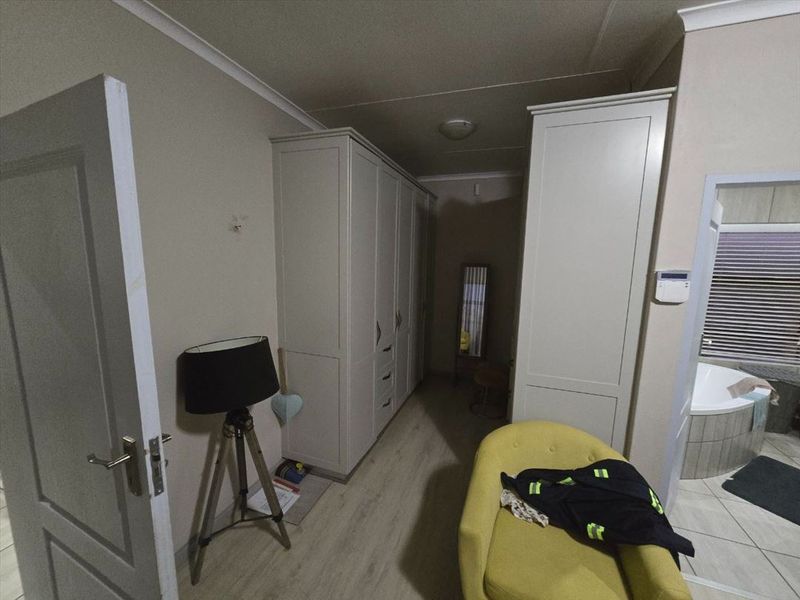 A bedroom featuring built-in cupboards, laminate flooring, and coved ceilings, with direct access to an adjoining bathroom.
