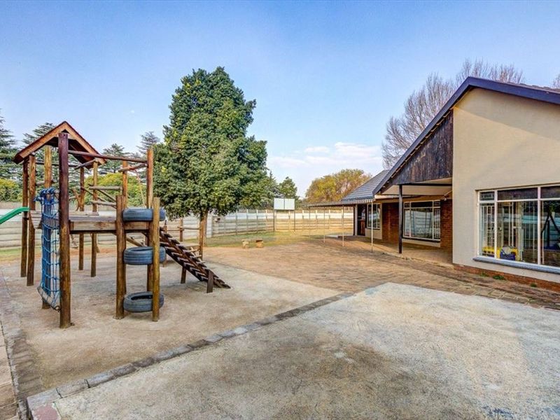 Spacious rear exterior area featuring a paved patio, covered veranda, and large windows, providing ample space for outdoor activities and entertainment.