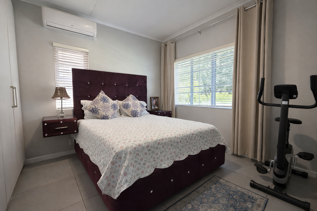 A well-maintained bedroom featuring tiled flooring, a built-in wardrobe, and a wall-mounted split-system air conditioner for climate control.