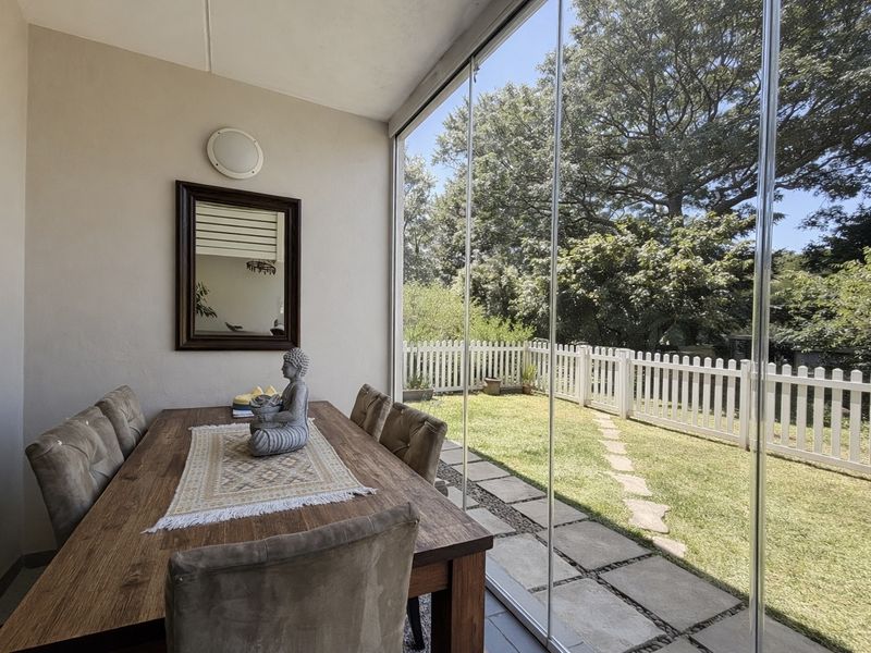 Enclosed patio area featuring frameless glass sliding doors, providing seamless indoor-outdoor flow to the private garden and lawn area.