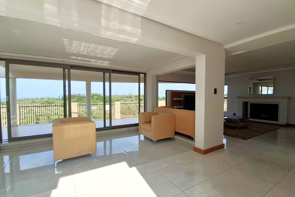 Spacious open-plan living area featuring large format floor tiles, a built-in fireplace, and expansive sliding glass doors leading to a covered patio.