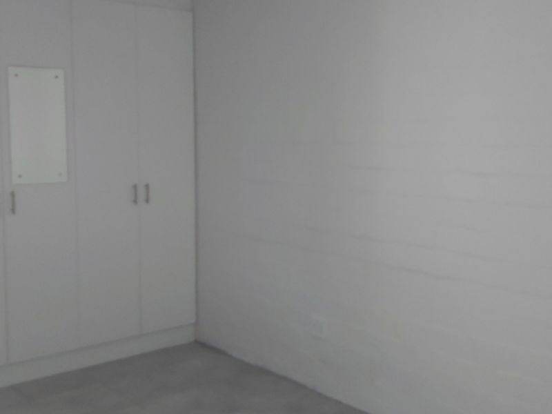 A simple, empty bedroom featuring white built-in cupboards and neutral flooring, providing a blank canvas for personalization.