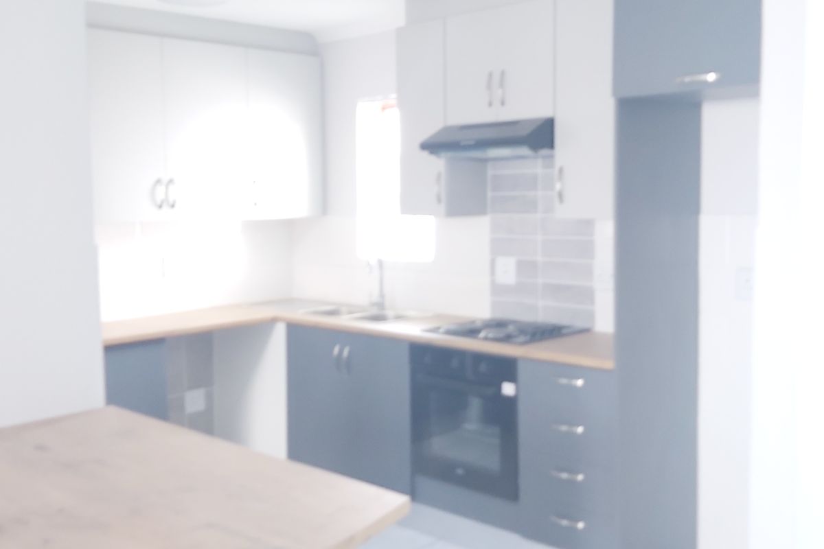 A modern kitchen featuring built-in cabinetry, a hob, an oven, and a tiled splashback, presented in a clean, functional layout.