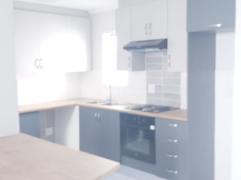 A modern kitchen featuring built-in cabinetry, a hob, an oven, and a tiled splashback, presented in a clean, functional layout.