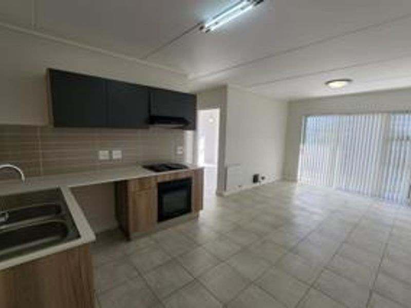 Spacious open-plan kitchen and living area featuring modern cabinetry, built-in appliances, tiled flooring, and large sliding doors leading to an outdoor space.
