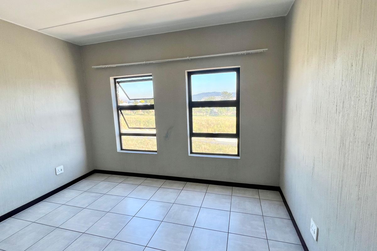 A clean, empty bedroom featuring neutral tiled flooring, modern aluminium window frames, and simple wall finishes, ready for personalization.