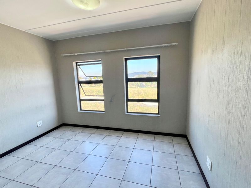 A clean, empty bedroom featuring neutral tiled flooring, modern aluminium window frames, and simple wall finishes, ready for personalization.