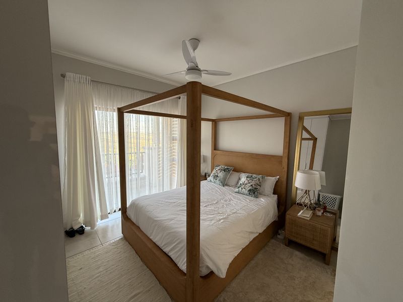 A well-maintained bedroom featuring tiled flooring, a ceiling fan, and a sliding glass door providing access to an outdoor area.