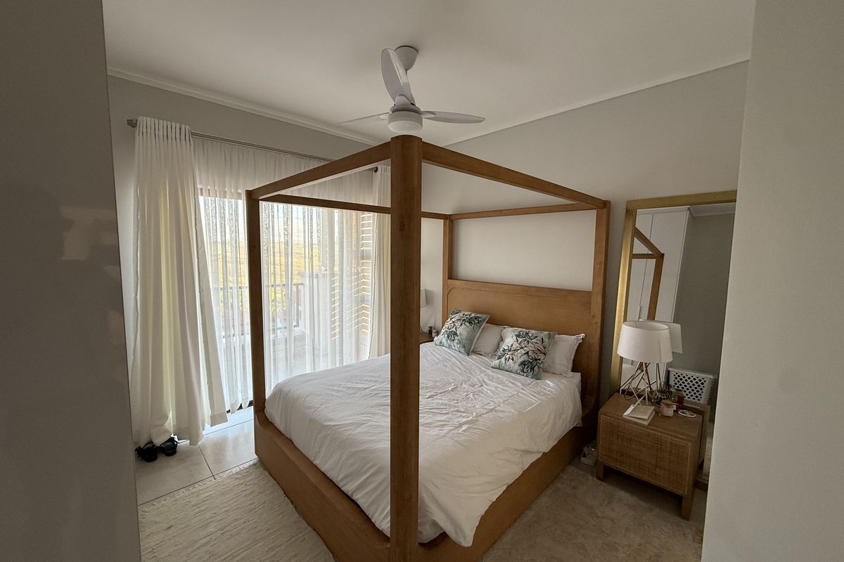 A well-maintained bedroom featuring tiled flooring, a ceiling fan, and a sliding glass door providing access to an outdoor area.