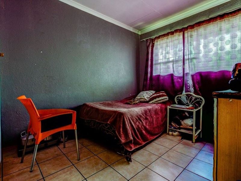 A bedroom featuring tiled flooring and dark painted walls, requiring cosmetic updates to improve the overall aesthetic and finish.