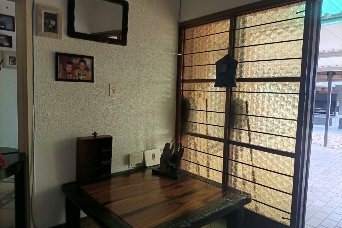 A living area featuring textured walls, tiled flooring, and a security gate leading to an outdoor patio space.