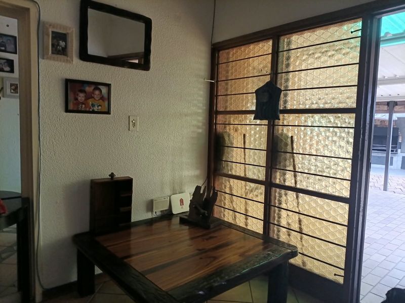 A living area featuring textured walls, tiled flooring, and a security gate leading to an outdoor patio space.