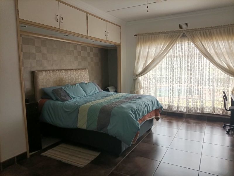 Spacious bedroom featuring built-in overhead cabinetry, tiled flooring, and large sliding glass doors providing natural light and access to the exterior.