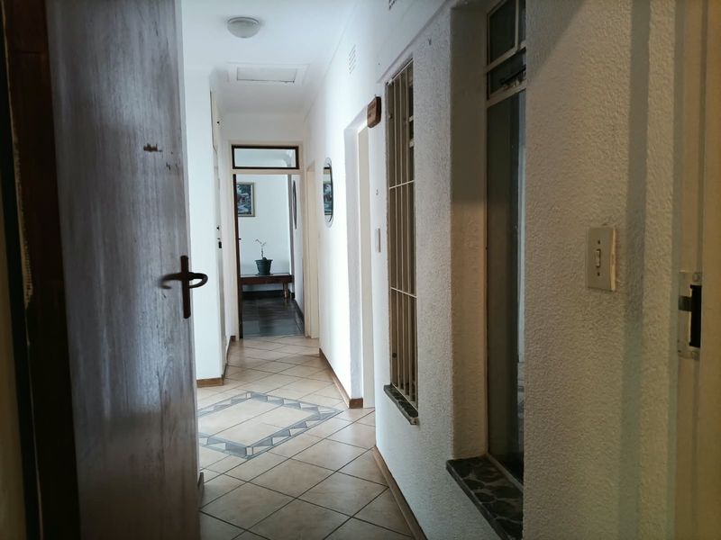 A functional hallway featuring tiled flooring, a security gate, and access to adjacent rooms, providing a clean and neutral transition space.