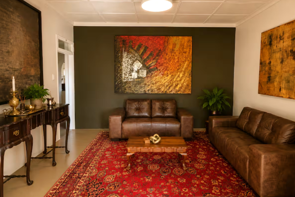 A well-maintained living room featuring a neutral tiled ceiling, flush mount lighting, and a dark accent wall.