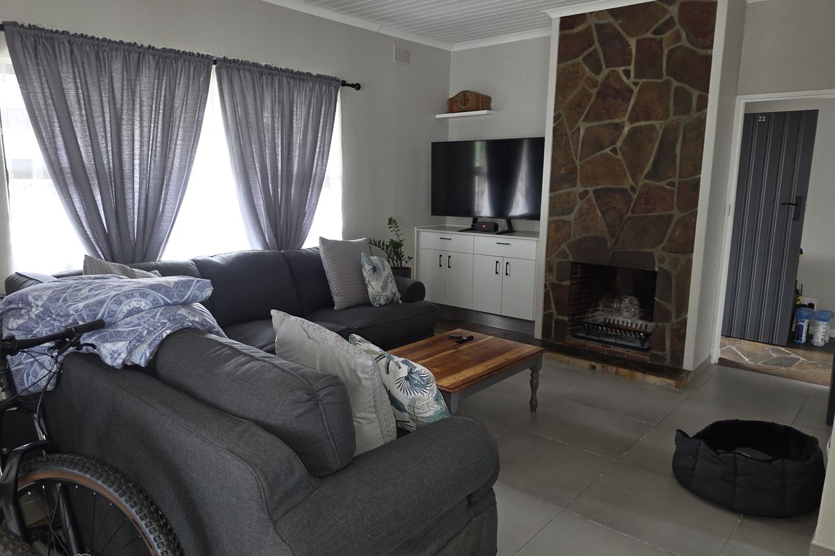 A living room featuring a prominent stone fireplace, tiled flooring, and built-in cabinetry, offering a cozy and functional space.