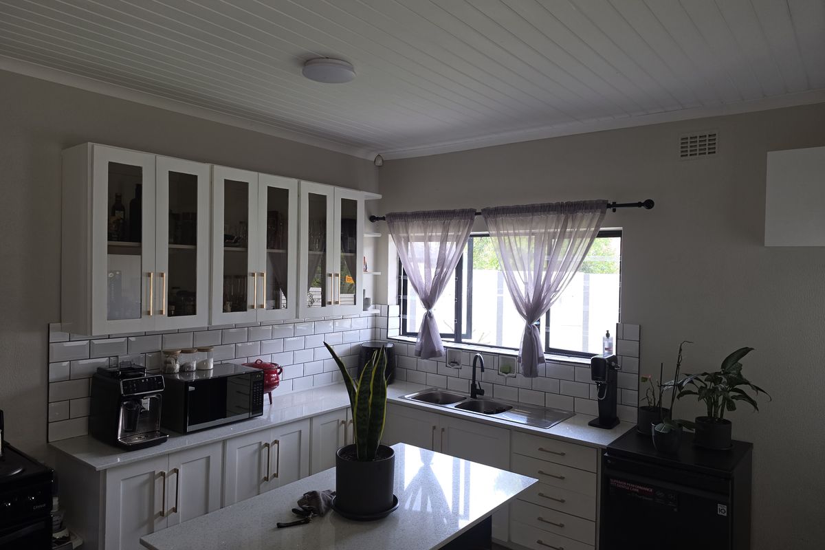 A well-maintained kitchen featuring white shaker cabinetry, quartz countertops, a subway tile backsplash, and a double basin sink with a modern faucet.