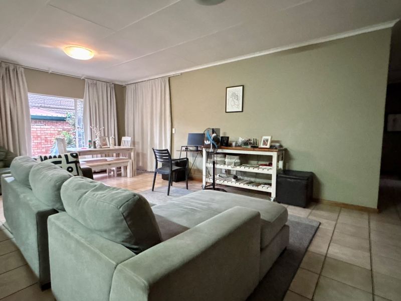 Spacious living area featuring neutral wall tones, tiled flooring, and large windows allowing for natural light.