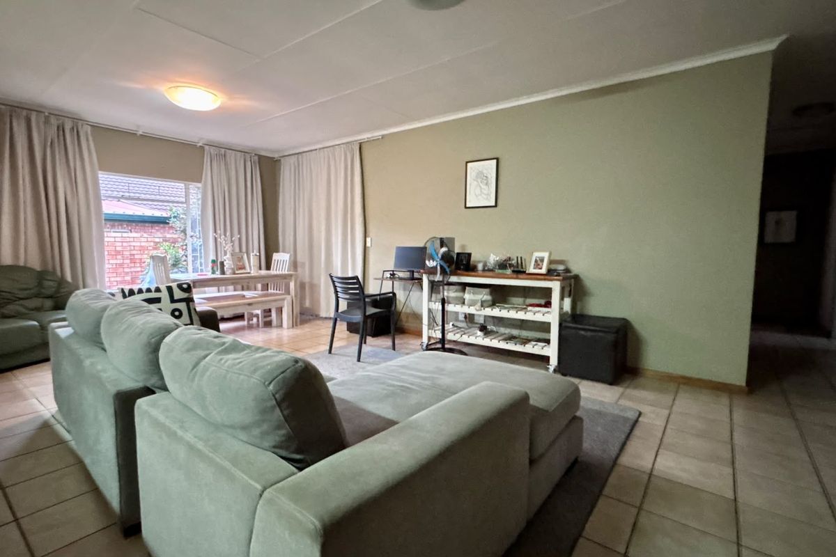 Spacious living area featuring neutral wall tones, tiled flooring, and large windows allowing for natural light.