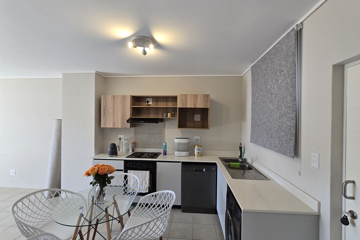 Modern kitchen featuring light wood-tone cabinetry, built-in oven and hob, double sink, and tiled flooring, offering a clean and functional workspace.