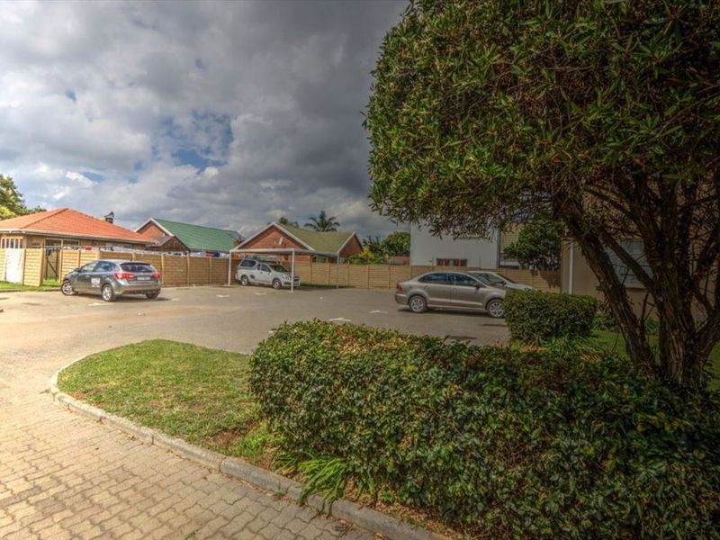 Exterior view of the apartment complex parking area featuring paved driveways, covered carports, and established garden landscaping.