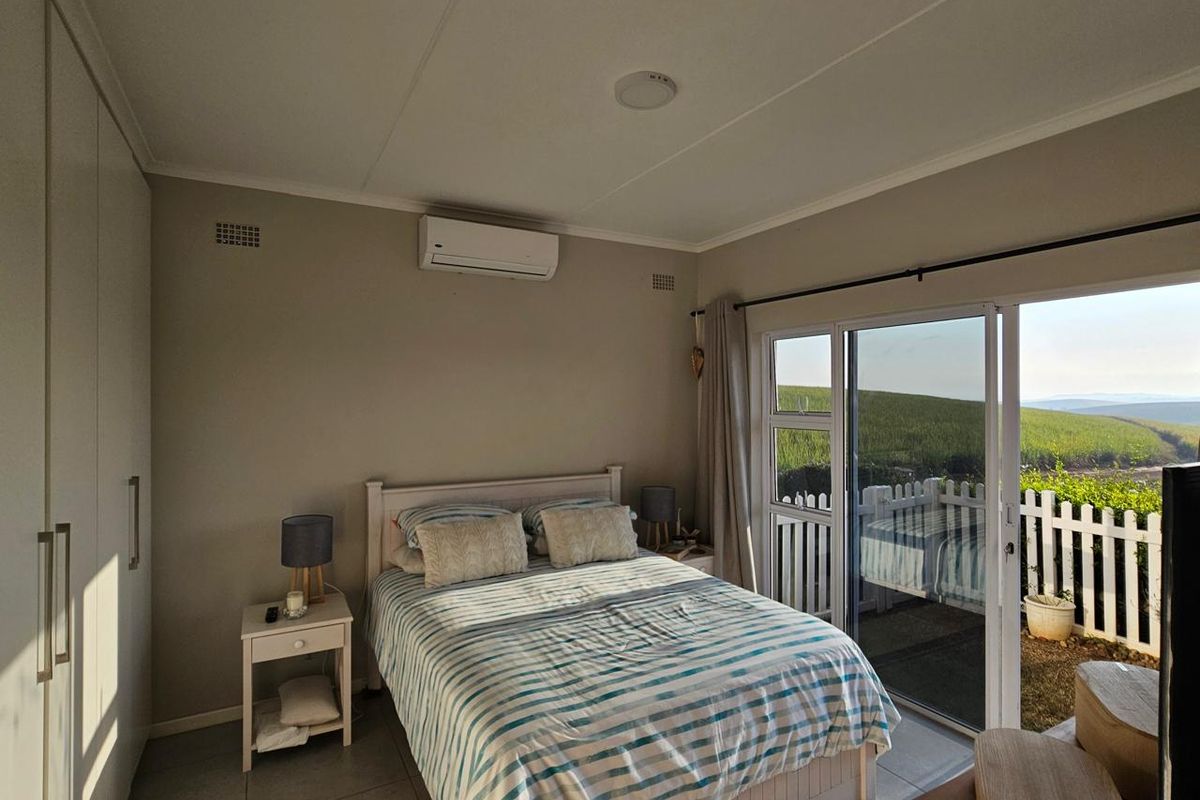 A well-maintained bedroom featuring built-in cupboards, an air conditioning unit, and large sliding glass doors that open to an outdoor area.