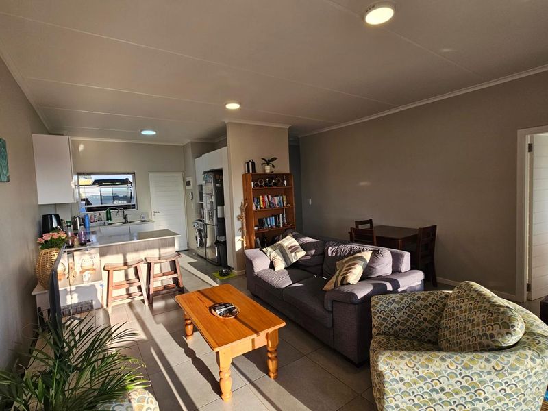 Open-plan living area featuring a functional kitchen with island, tiled flooring, and recessed lighting, creating a cohesive space for dining and relaxation.