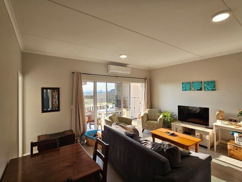 An open-plan living area featuring tiled floors, a split-system air conditioner, and large sliding glass doors that provide access to an outdoor patio.