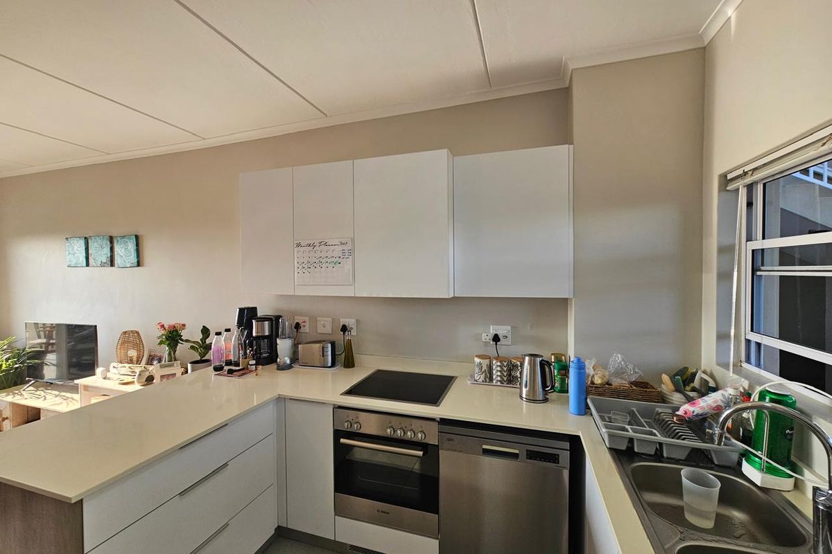 Modern kitchen featuring white cabinetry, stone countertops, built-in oven, electric hob, and a stainless steel dishwasher with a double bowl sink.