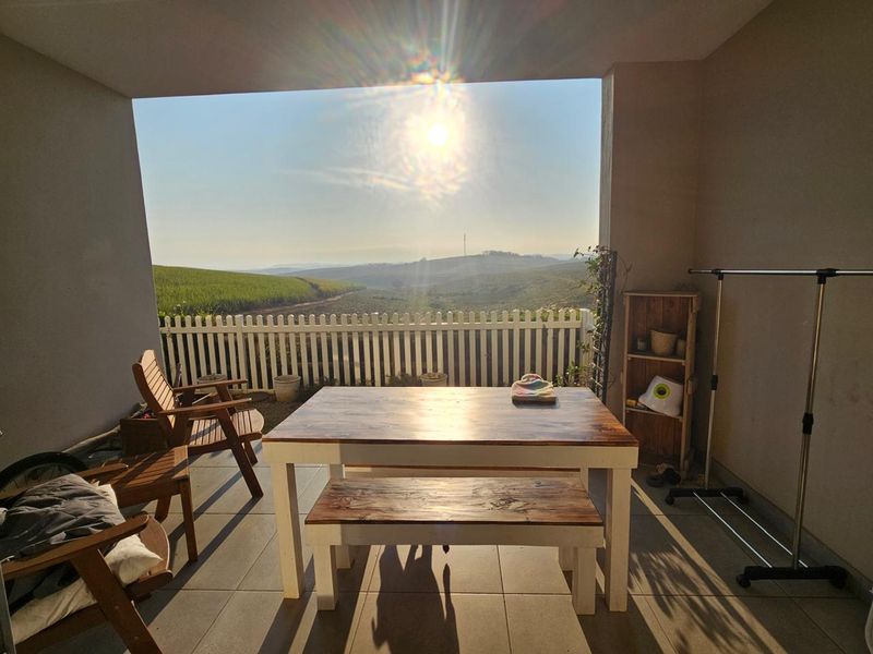A covered balcony featuring tiled flooring and a picket fence railing, offering expansive views of the surrounding landscape.