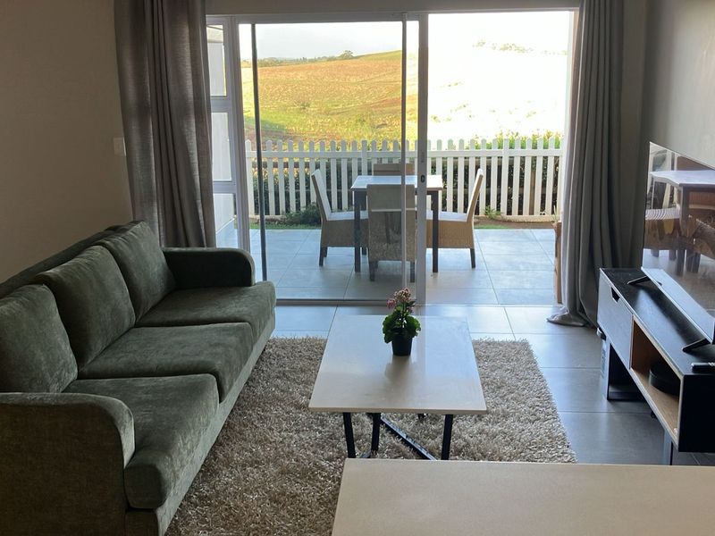 Bright living room featuring large sliding glass doors that open onto a private patio with scenic views.
