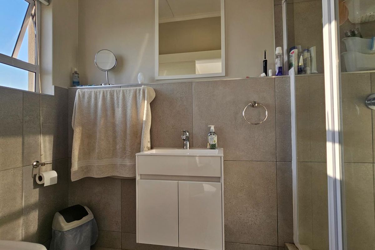 Modern bathroom featuring a wall-mounted vanity, tiled finishes, and a glass-enclosed shower, offering a clean and functional space.