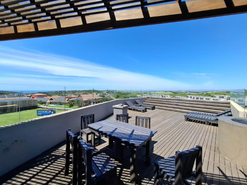 Spacious rooftop terrace featuring timber decking, a pergola, glass balustrades, and a built-in fire pit with expansive panoramic views.