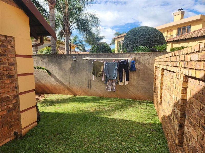 A private rear garden area featuring a lawn, brick boundary walls with electric fencing, and a wall-mounted clothesline.