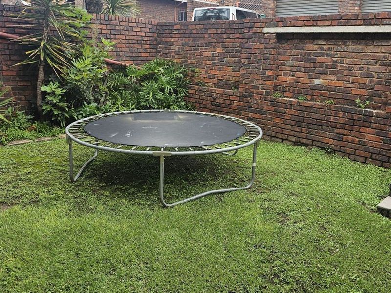 A private rear garden area enclosed by a brick boundary wall, featuring a lawn space that requires maintenance.