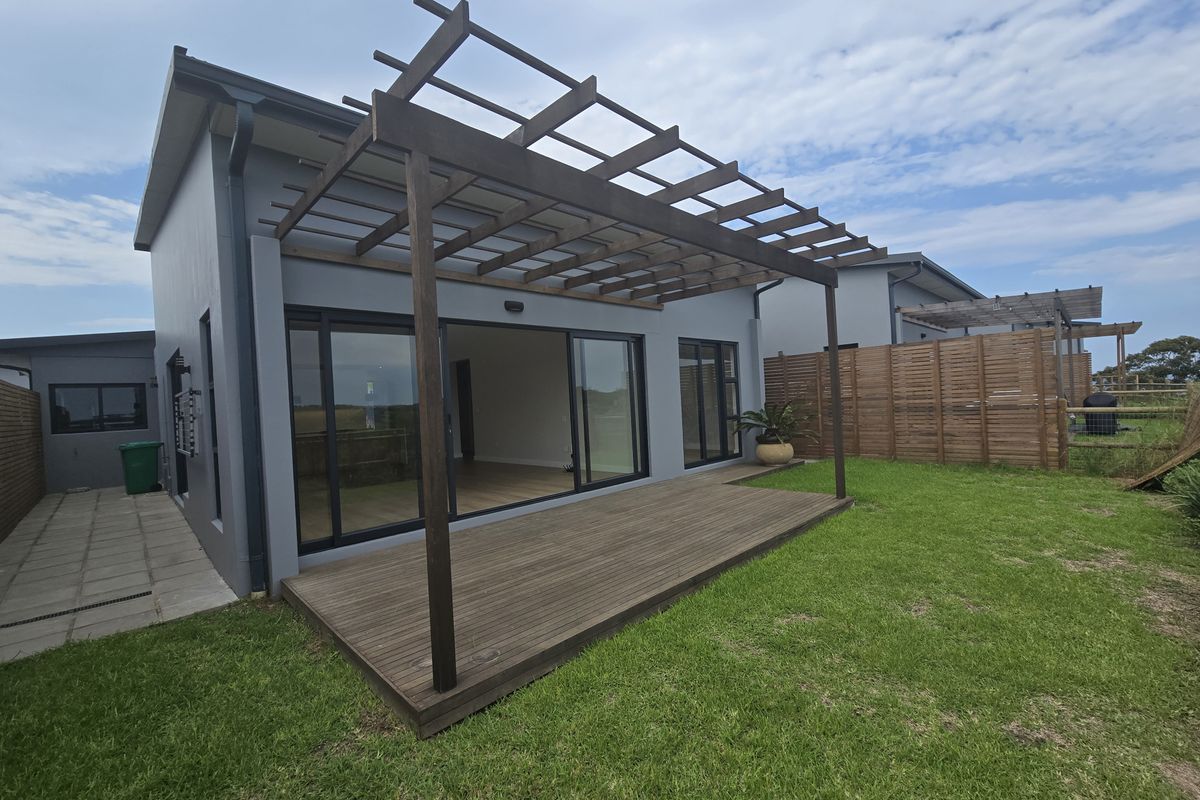 Rear view of the property featuring a timber pergola over a wooden deck, sliding glass doors, and a private garden area.