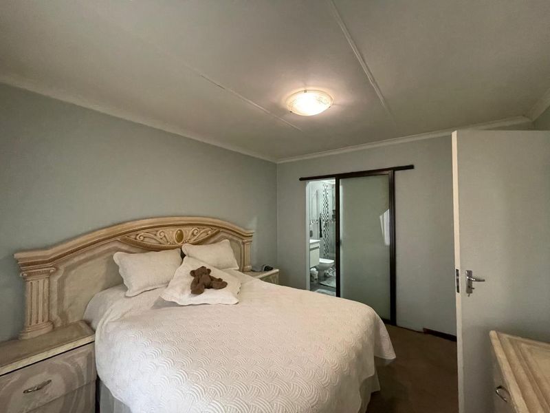 A bedroom featuring a sliding door leading to an en-suite bathroom, with neutral wall tones and a flush mount ceiling light fixture.