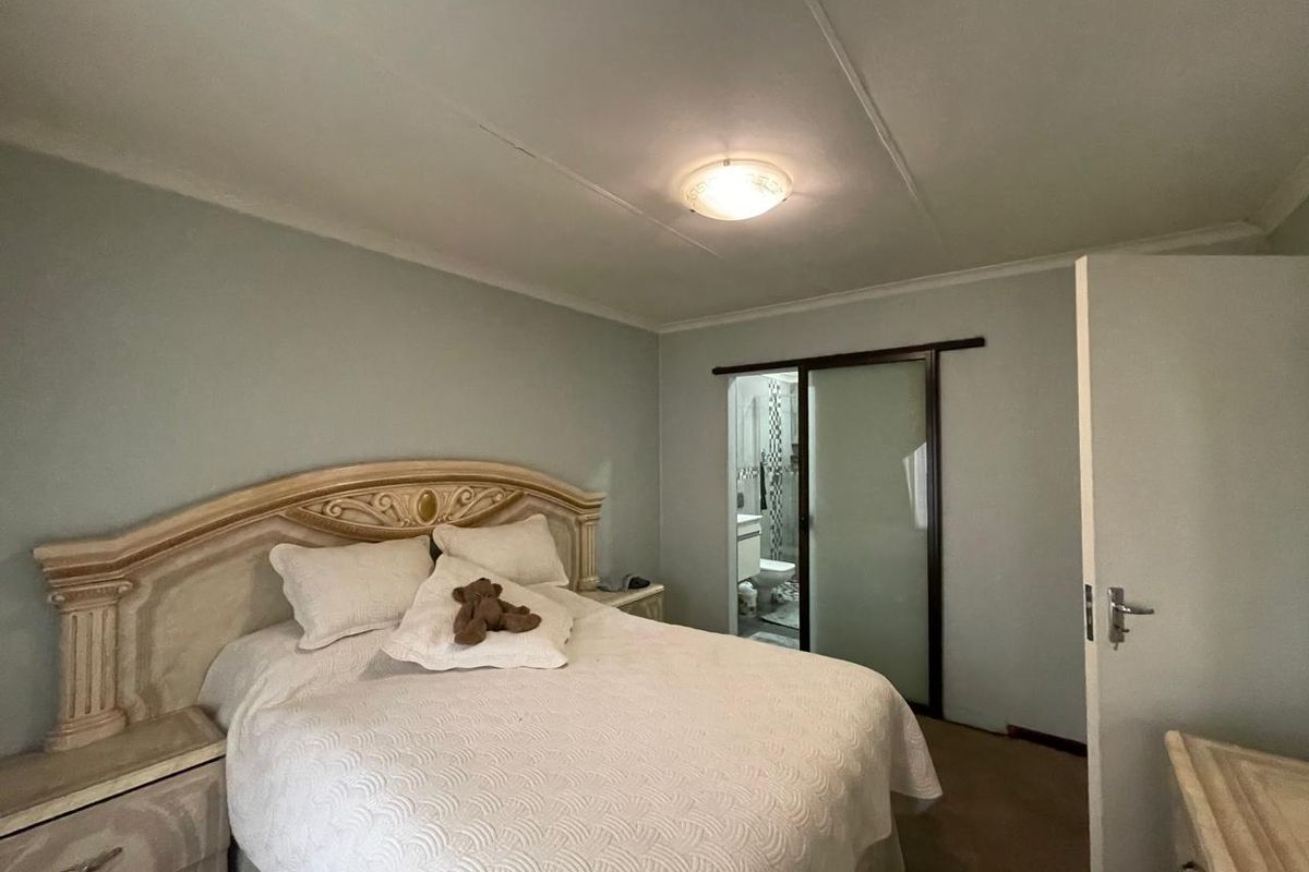 A bedroom featuring a sliding door leading to an en-suite bathroom, with neutral wall tones and a flush mount ceiling light fixture.