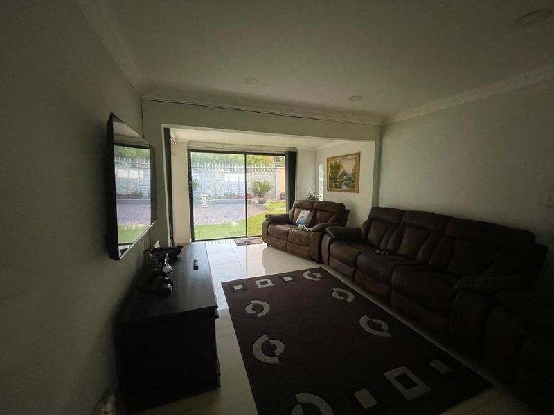 A comfortable living room featuring tiled flooring, recessed lighting, and large sliding glass doors that provide direct access to the rear garden area.