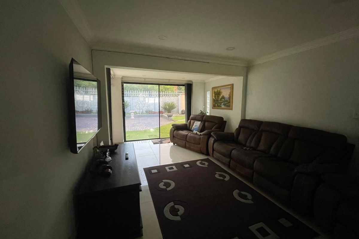 A comfortable living room featuring tiled flooring, recessed lighting, and large sliding glass doors that provide direct access to the rear garden area.