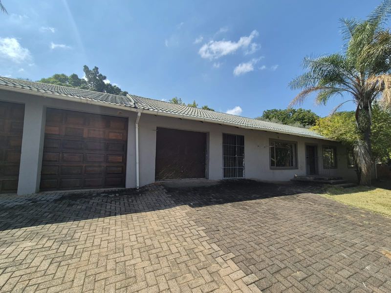 Front exterior view of the house featuring a paved driveway, multiple garage doors, and a tiled roof structure.