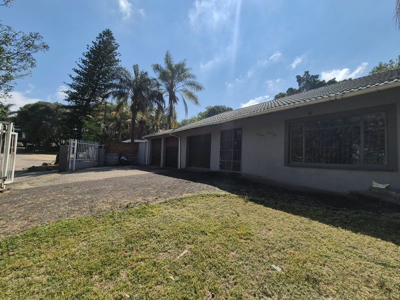 Front exterior view of the property featuring a paved driveway, multiple garage doors, and security gates with a tiled roof.