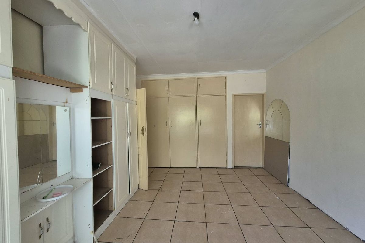 An empty bedroom featuring extensive built-in cabinetry, a built-in vanity unit, and tiled flooring throughout.