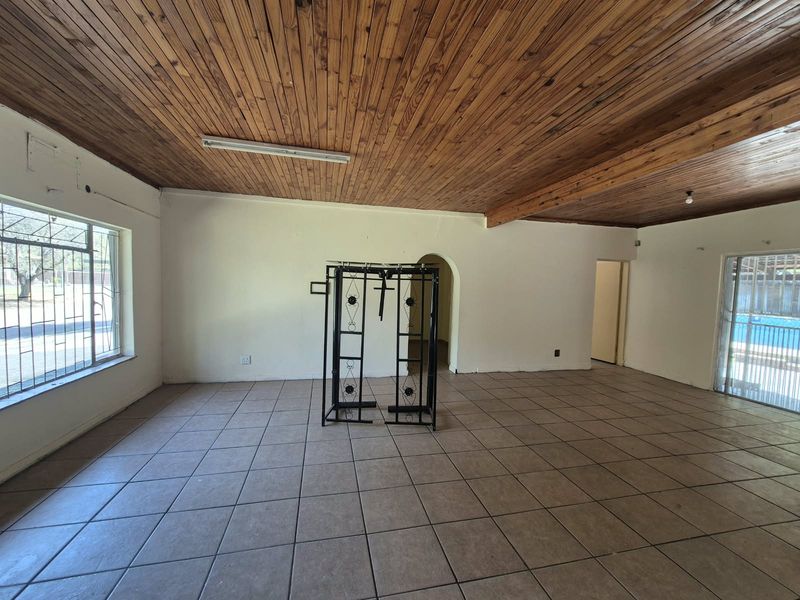 Spacious living area featuring ceramic floor tiles, a timber-clad ceiling, and an arched doorway leading to adjacent rooms.