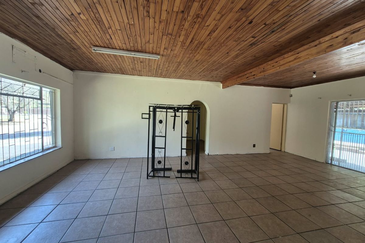 Spacious living area featuring ceramic floor tiles, a timber-clad ceiling, and an arched doorway leading to adjacent rooms.